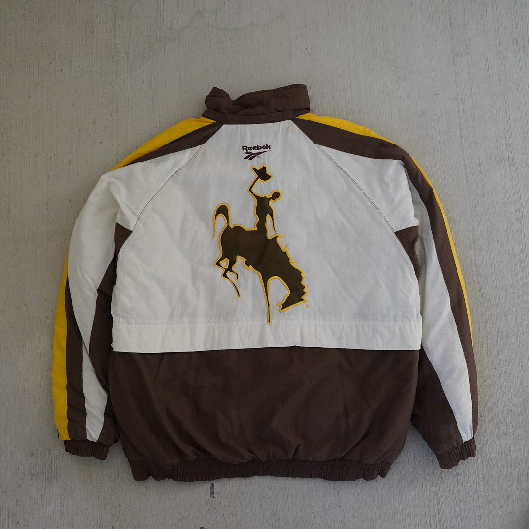 Vintage 1990s Reebok Pro Line Wyoming Cowboys jacket in brown, gold, and white with embroidered logos and large back graphic — Vintage Wyoming Gear Collection, West Block Vintage.
