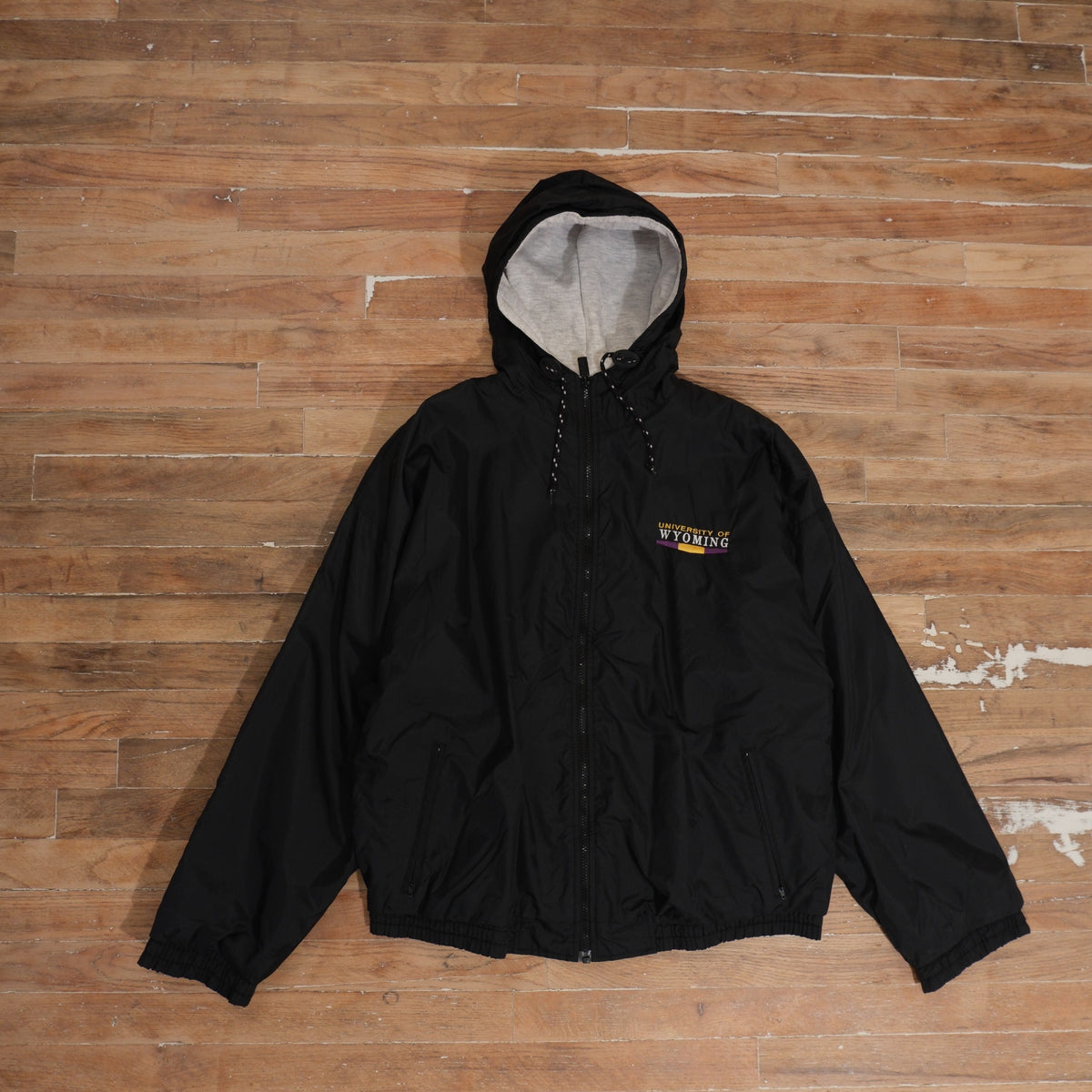 Black 1990s University of Wyoming full-zip hooded windbreaker with embroidered chest detail and gray hood lining