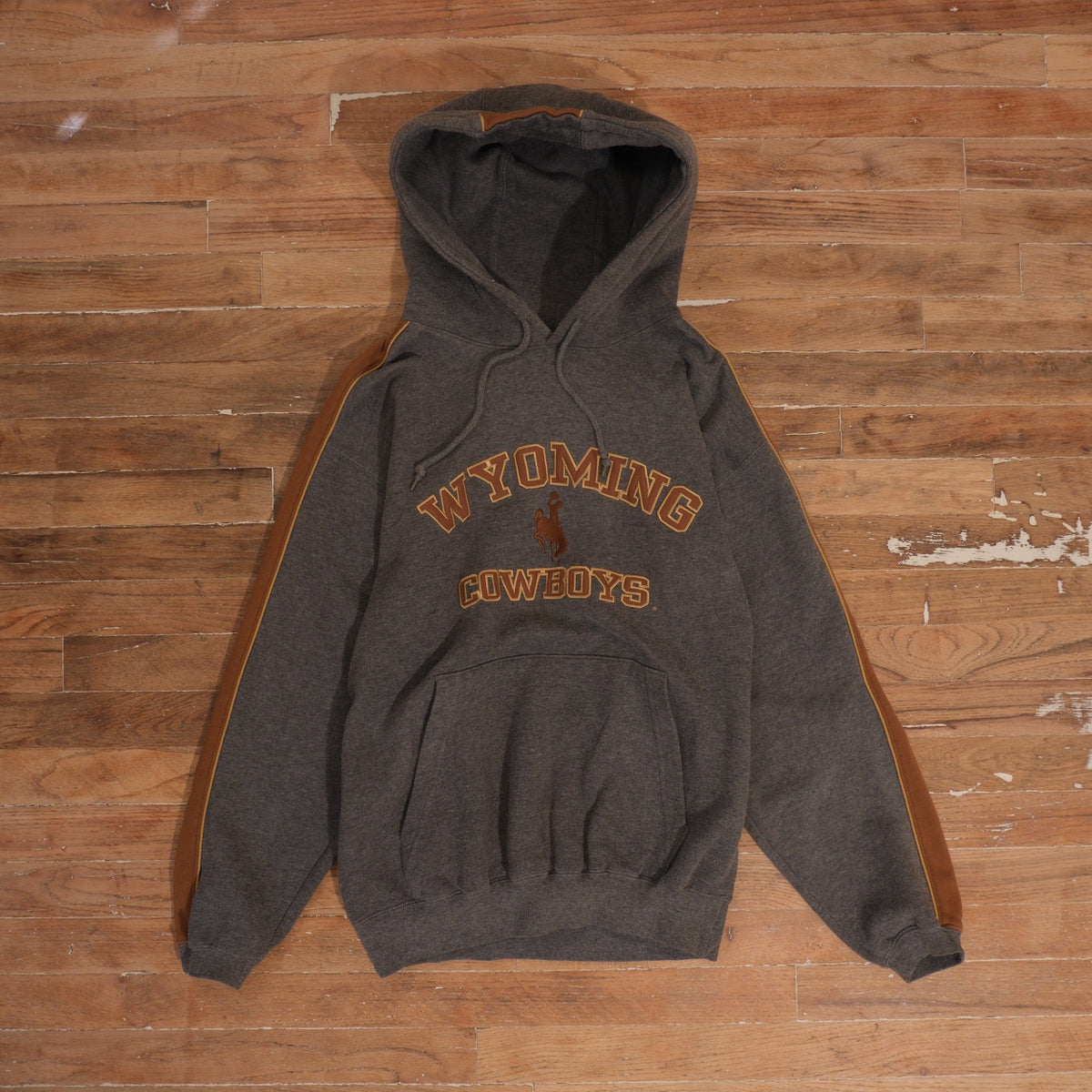 Charcoal gray Wyoming Cowboys embroidered hoodie with rust-brown colorblock sleeves and front kangaroo pocket
