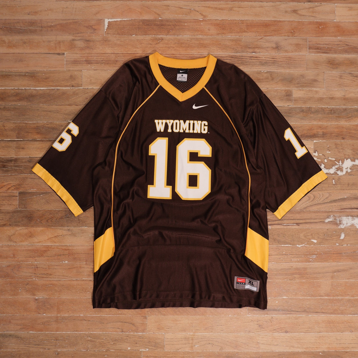 Mid-2000s brown / gold / white Nike Wyoming Cowboys Number 16 Brown Football Jersey photographed flat on wood floor