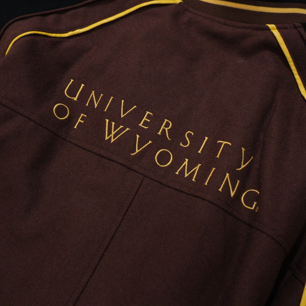 1990s brown / black / gold College Gate Wyoming Cowboys Brown Black Track Jacket photographed flat on wood floor front detail