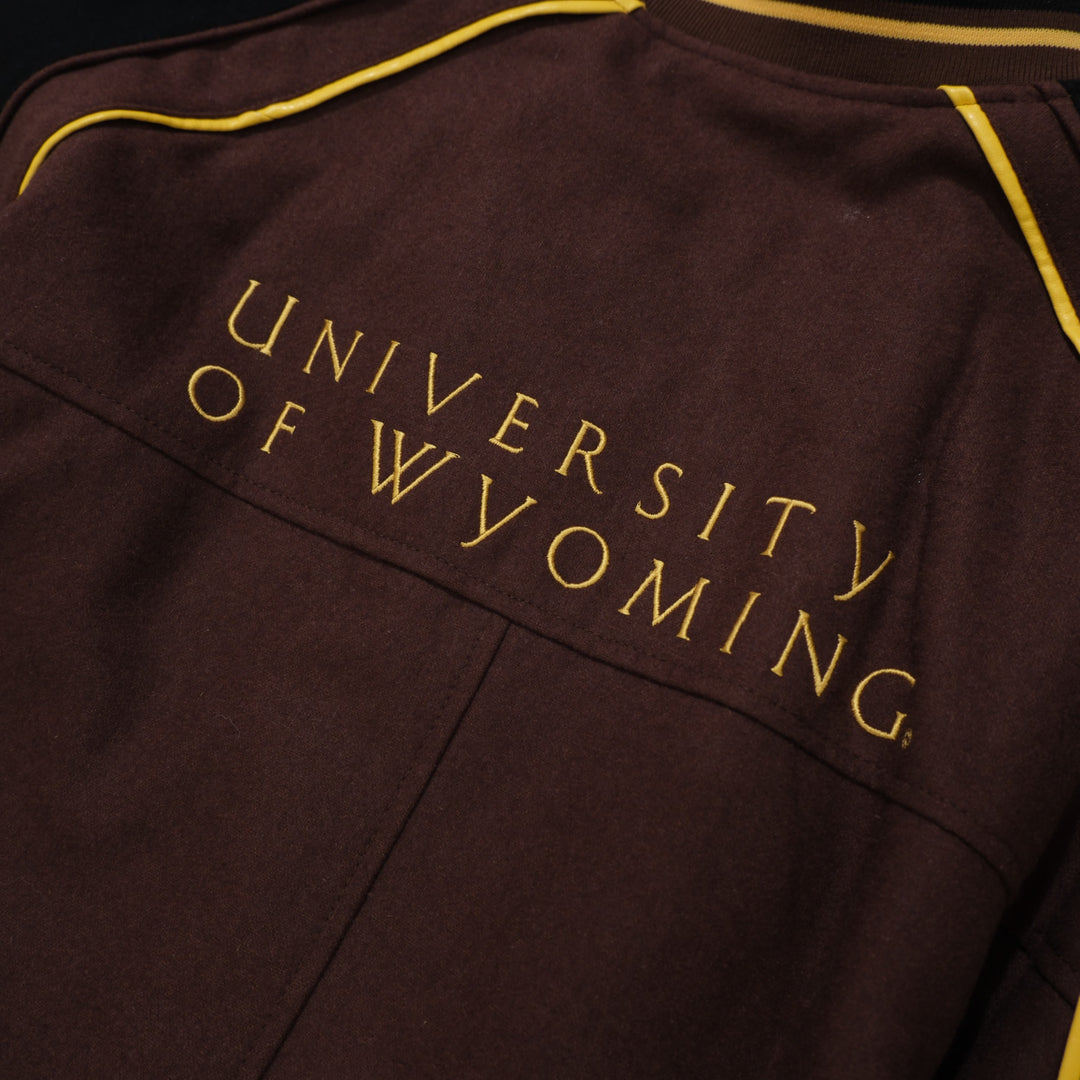 1990s brown / black / gold College Gate Wyoming Cowboys Brown Black Track Jacket photographed flat on wood floor front detail