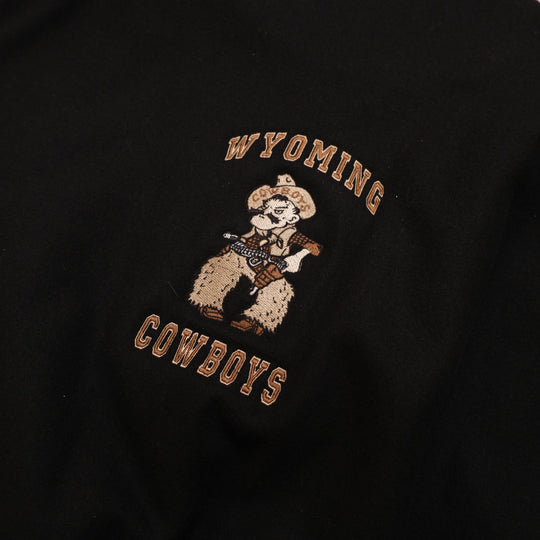 Y2K black / brown / cream Wyoming Cowboys Black Leather Sleeve Varsity Jacket photographed flat on wood floor front detail