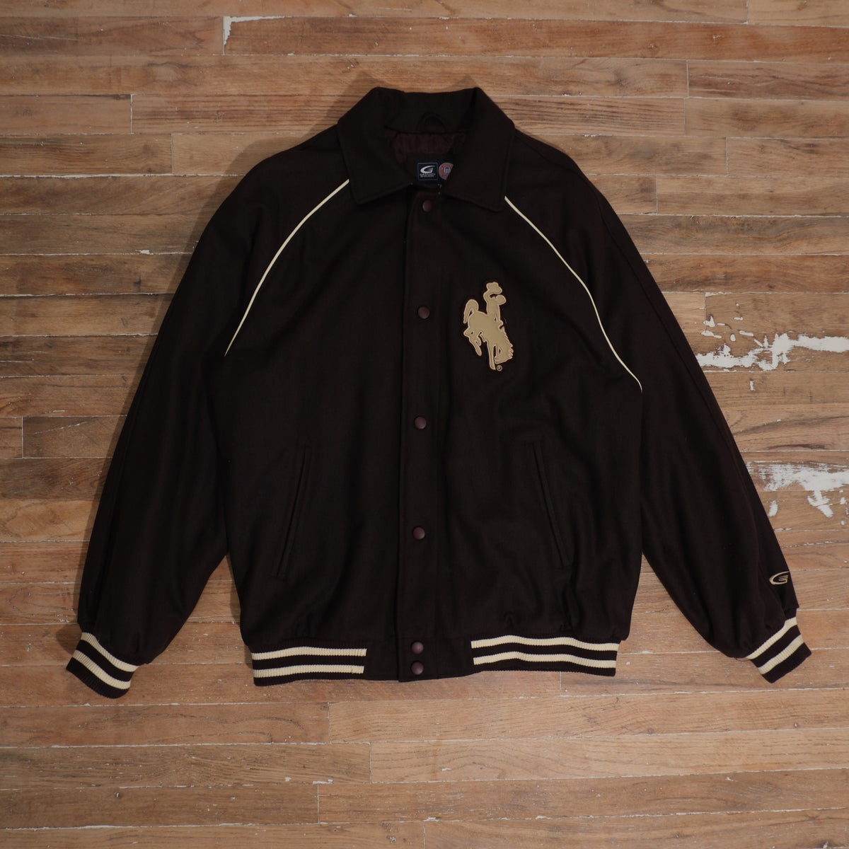 Y2K dark brown / cream / gold Wyoming Cowboys Steamboat Patch Brown Varsity Jacket photographed flat on wood floor