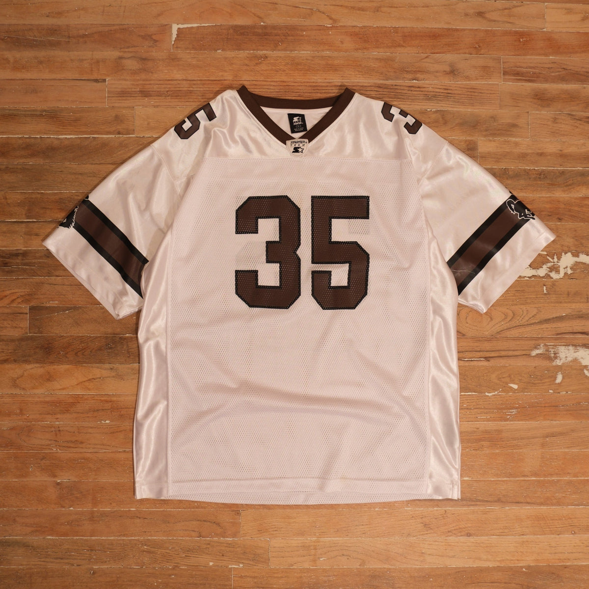 1990s white / brown / black Starter Wyoming Cowboys 35 White Mesh Football Jersey photographed flat on wood floor
