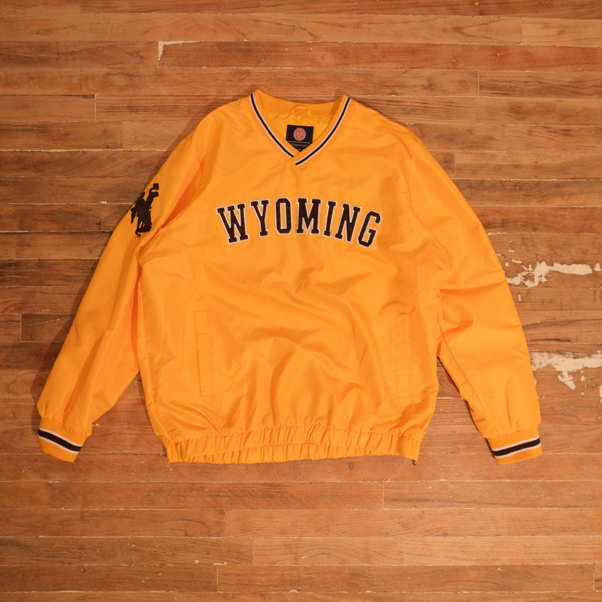 Mid-2000s Wyoming Cowboys gold / brown / white windbreaker wyoming cowboys gold steamboat v-neck windbreaker front flat lay