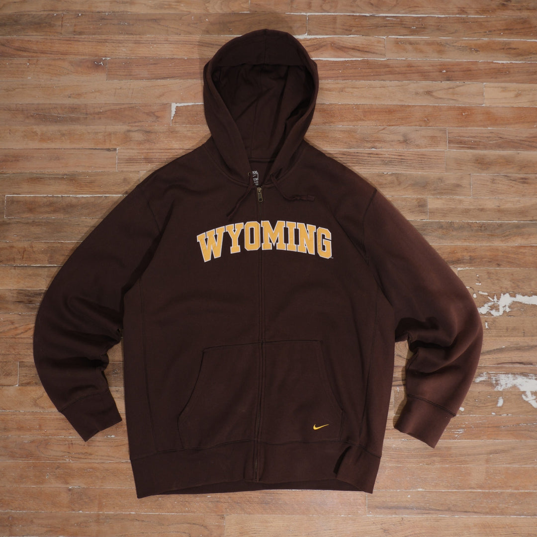 Mid-2000s Nike Wyoming Cowboys chocolate-brown full-zip hoodie with arched gold Wyoming lettering, small embroidered Nike Swoosh, drawstring hood, and sun fading on right sleeve.