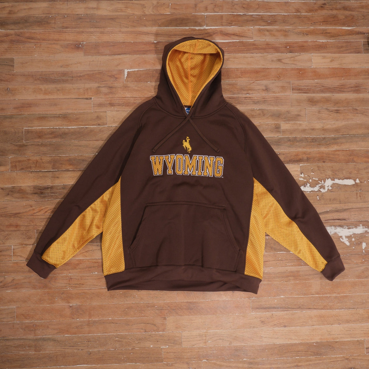 Mid-2000s Wyoming Cowboys brown pullover hoodie with gold mesh sleeve and side panels, mesh-lined hood, textured Wyoming chest lettering, and Steamboat logo.